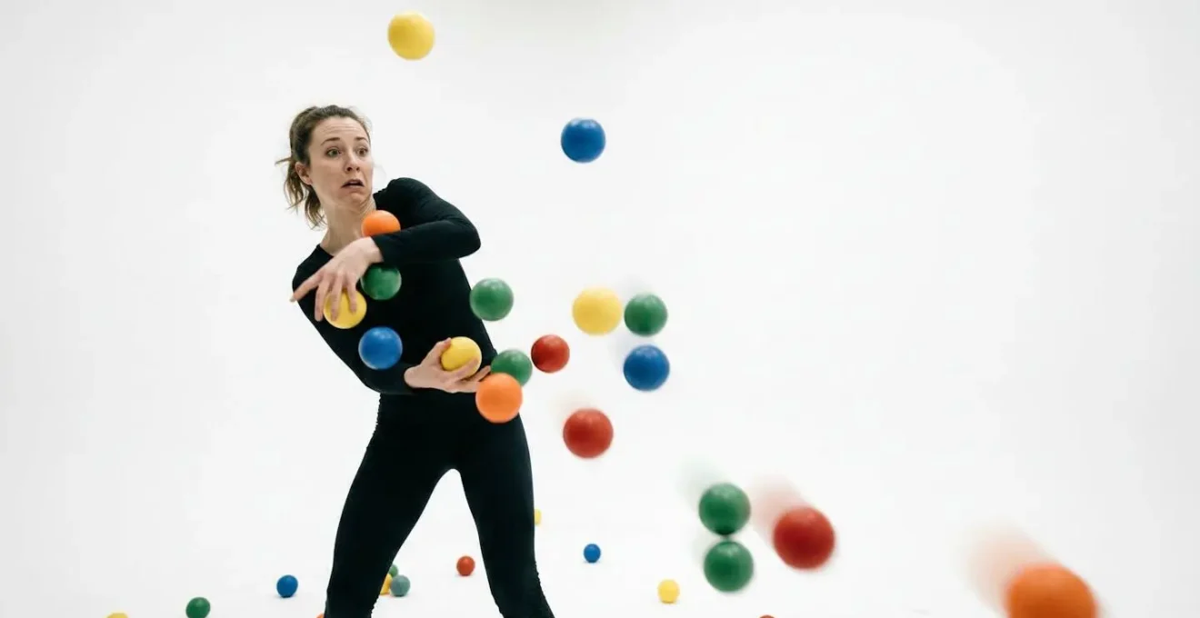 Jongleur laissant tomber des balles colorées, métaphore de l'attention fragmentée par le multitâche.